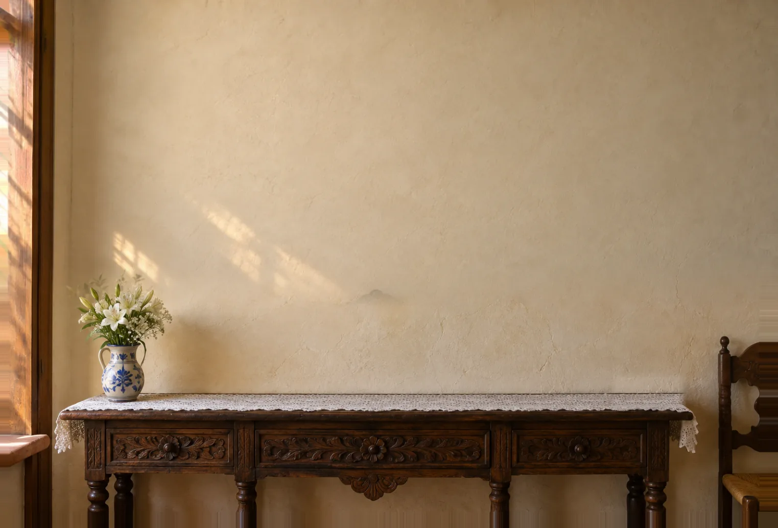 Una sala con una mesa de madera, rosas de Castilla en un jarro de talavera y una pared de imágenes religiosas enmarcadas